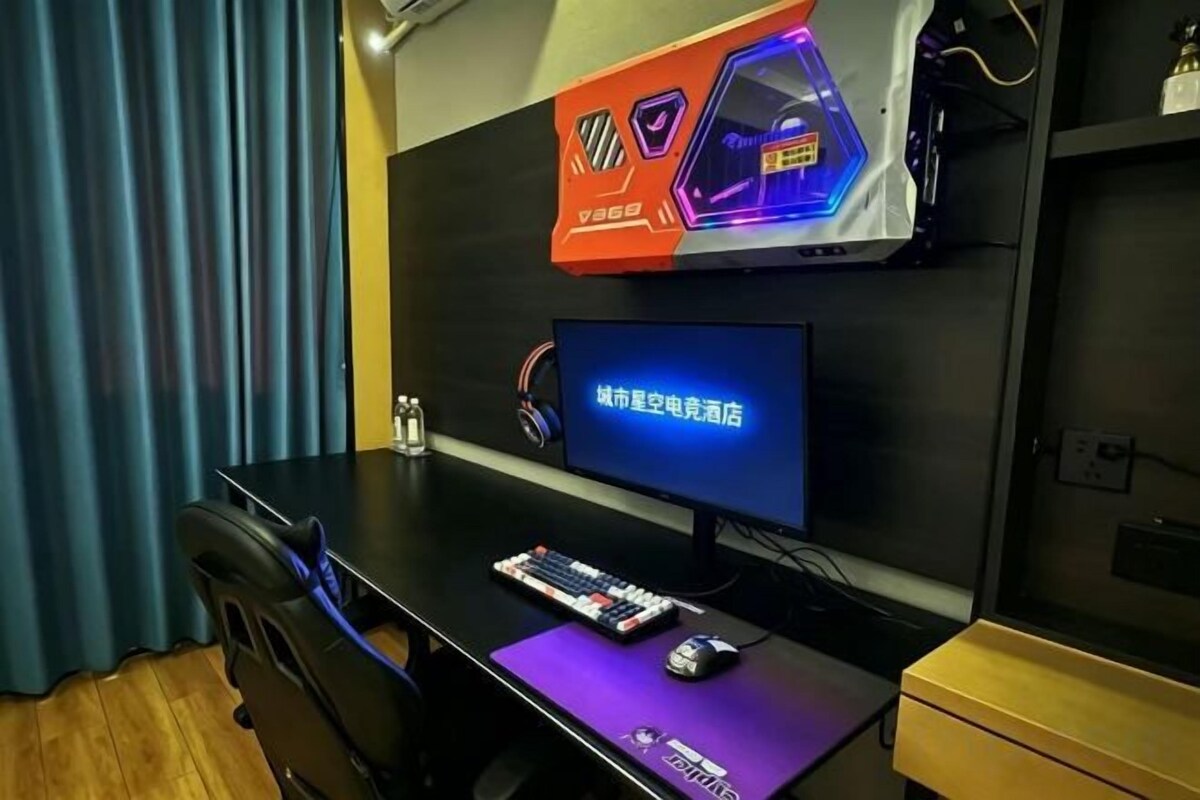 A room with a desk, a computer monitor, a keyboard, a mouse, and a pair of headphones.