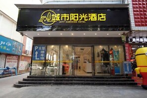 A hotel entrance with a large glass facade, a signboard, and a visible parking sign. - City Express Hotel (Longzhou)