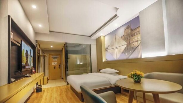 A hotel room with a bed, a desk, a television, a sofa, and a painting on the wall. - City Express Hotel (Longzhou)