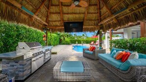 Un patio exterior con una parrilla, una zona de estar y una piscina.