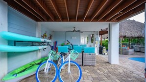 Un espacio al aire libre cubierto con piscina, una bicicleta y kayaks.