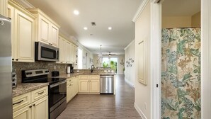 Una cocina con armarios de tonos claros, un refrigerador de acero inoxidable, un microondas, una estufa y un lavavajillas.