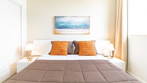 Ein ordentlich eingerichtetes Hotelzimmer mit einem großen Bett, zwei Kissen, zwei Nachttischen mit Lampen und einem Bild an der Wand.