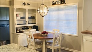 Una cocina con comedor, un letrero de cafetería y un cartel con la palabra 'GATHER' en la pared.