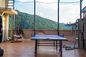 A ping pong table on a balcony with a netted enclosure, a hanging chair, and exercise equipment. - Manshanhong International Hotel (Quanzhou)