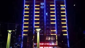 Um edifício alto com linhas verticais iluminadas e uma entrada bem iluminada.