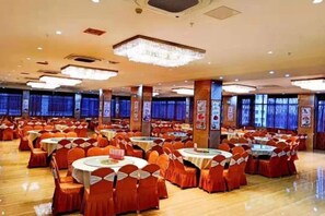 A banquet hall with round tables and chairs, large windows, and a chandelier. - Manshanhong International Hotel (Quanzhou)