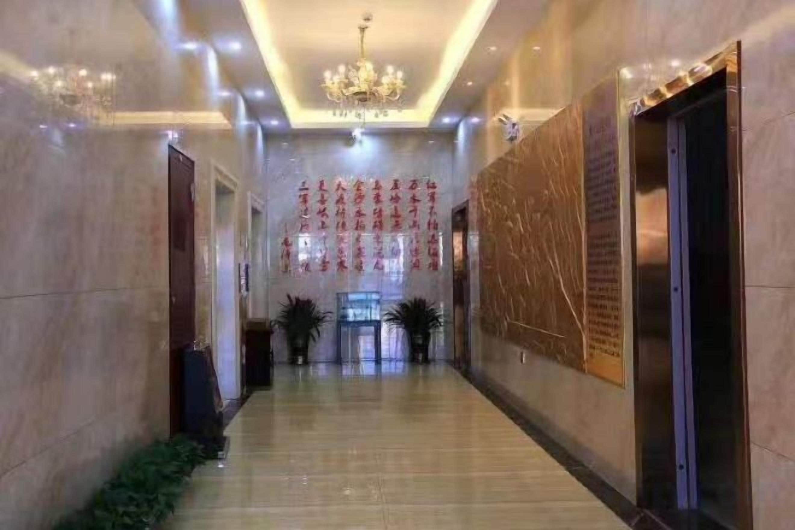 Un pasillo de hotel con piso de mármol, un candelabro y una pared con texto.
