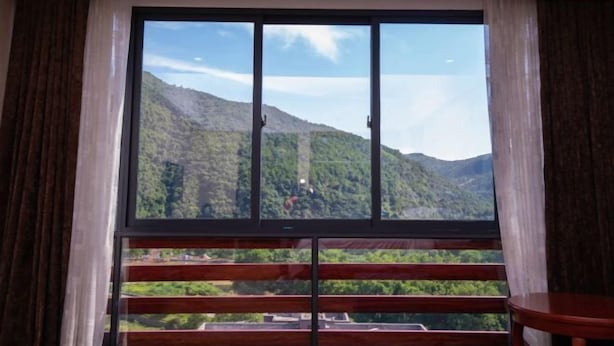 Quarto com uma grande janela que oferece vista para uma paisagem montanhosa.