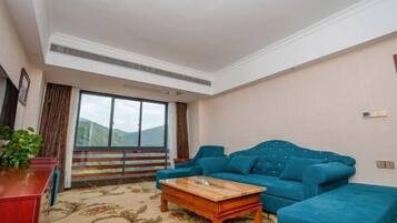 A living room with a sofa, a coffee table, a red cabinet, and a large window with a view of mountains.