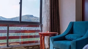 Quarto com uma janela grande, um sofá azul e uma pequena mesa de madeira.