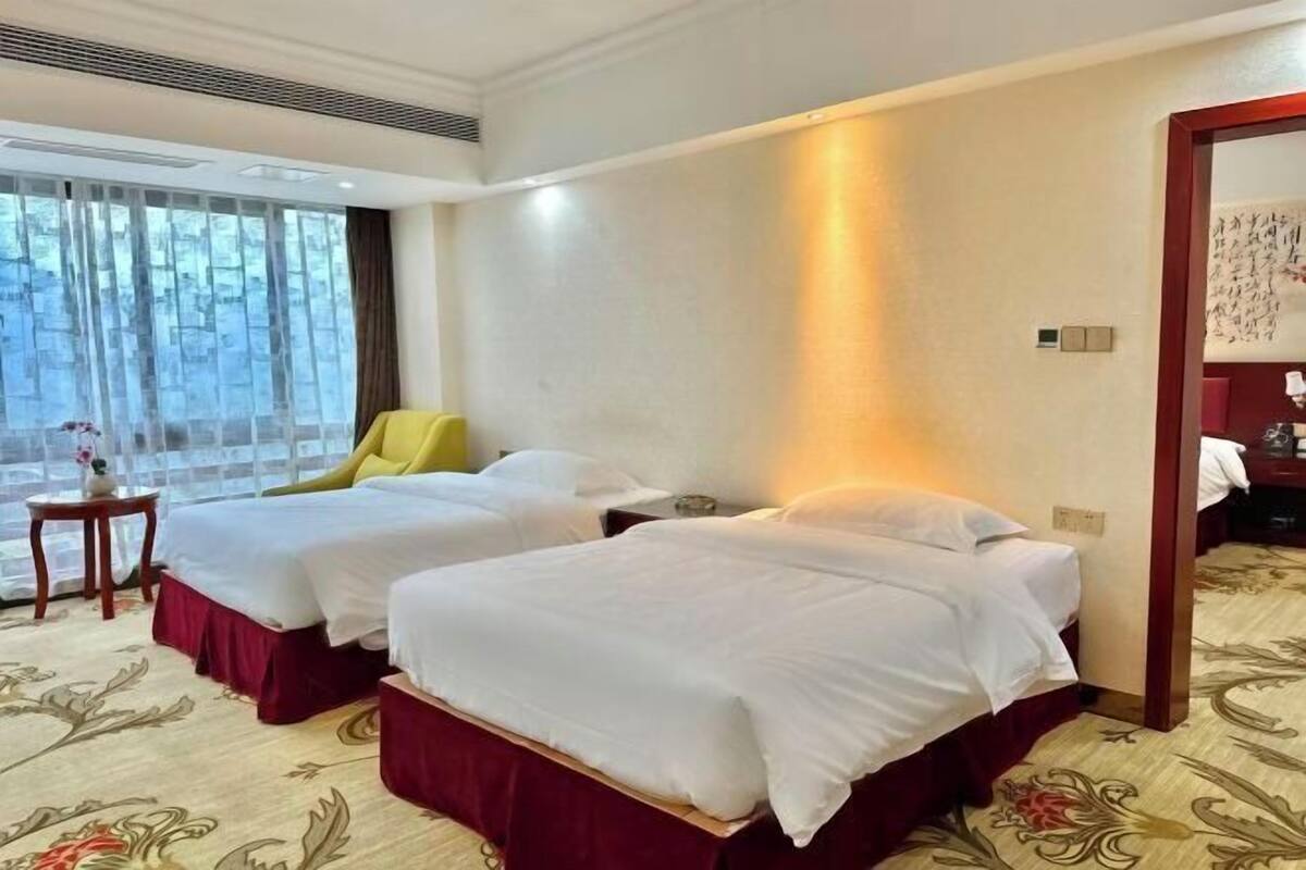 A hotel room with two beds, a small table, and a chair.