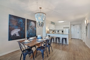 A dining area with a wooden table and chairs, a chandelier, and artwork on the walls.