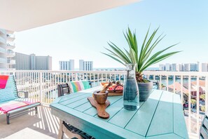 A balcony with a table, a plant, a wooden bowl, and a pitcher. - 🌞Terrace at Pelican Beach 702 - Good Day Sunshine | Family Friendly Amenities🌞 (Destin)