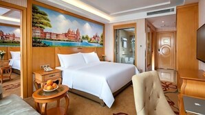 A hotel room with a large bed, a desk, a chair, a television, and a painting of a cityscape. - Vienna Hotel (Jiujiang Duchangxin Bus Station) (Duchang)