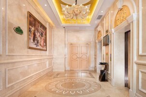 Un pasillo con una puerta de madera grande, un candelabro y un piso con diseño.