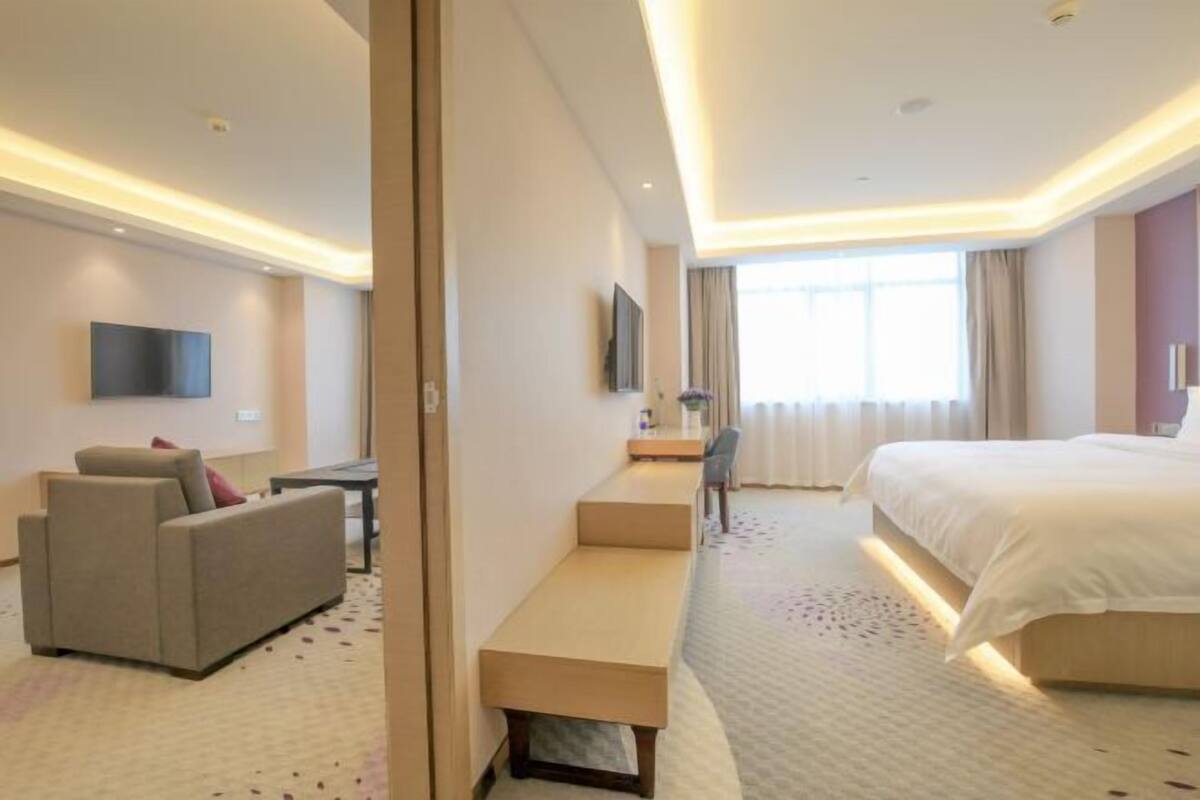 A hotel room with a bed, a sofa, a desk, and a TV.