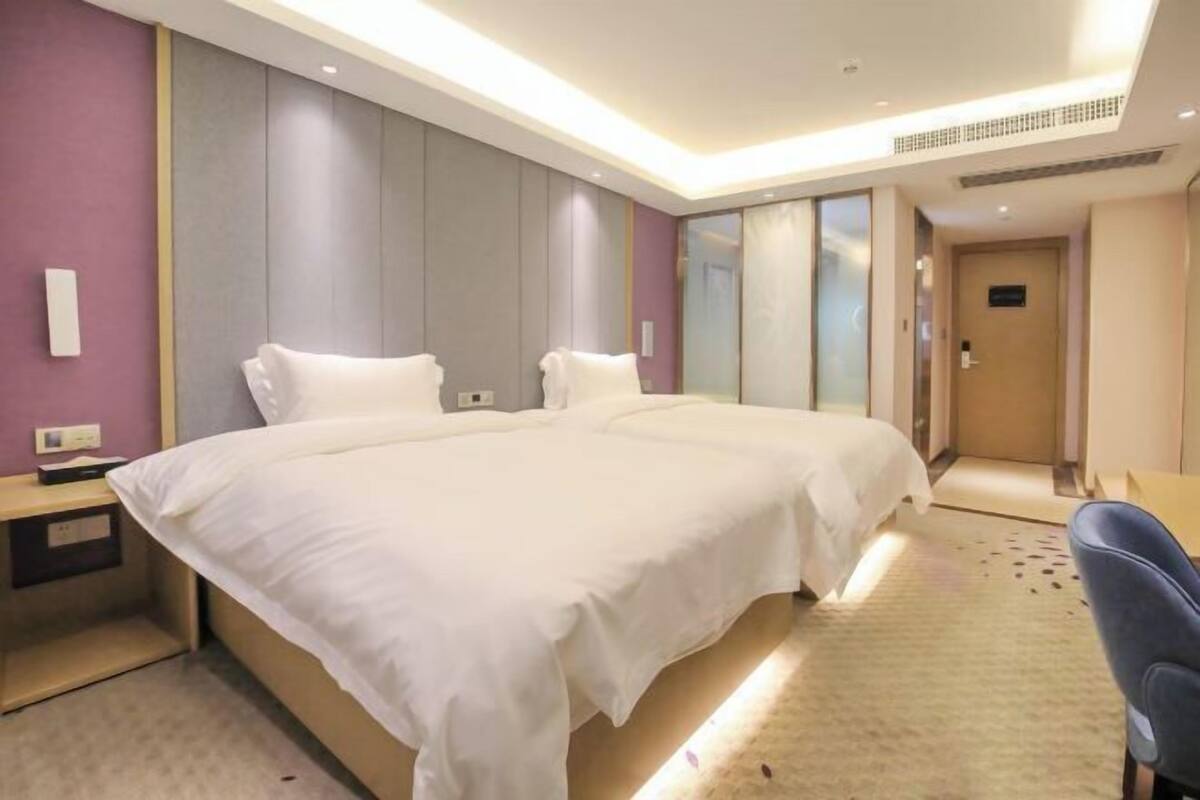 A hotel room with a large bed, bedside tables, a desk, and a chair.