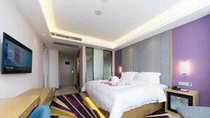 A hotel room with a bed, a desk, a chair, a TV, and a bedside table. - Lavande Hotel (Foshan)