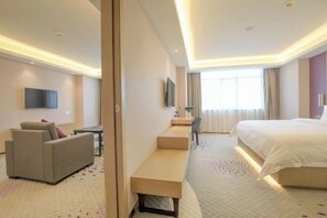 A hotel room with a bed, a sofa, a desk, and a TV. - Lavande Hotel (Foshan)