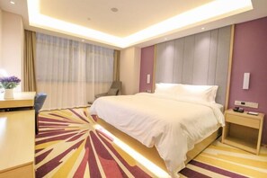 A modern hotel room with a large bed, a desk, and a chair.