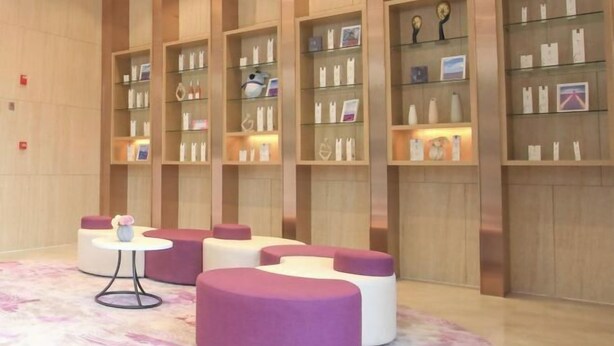 A modern lobby with a circular seating area, wooden paneling, and glass display shelves with various items. - Lavande Hotel (Foshan South Railway Station Bijiang Light Rail Station) (Foshan)