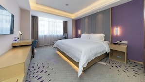 A hotel room with a bed, bedside table, desk, chair, and a large window. - Lavande Hotel (Foshan)
