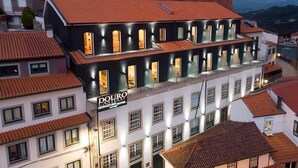 A hotel with a white facade and red-tiled roof, featuring multiple balconies and a sign that reads "Douro Signature Hotel."