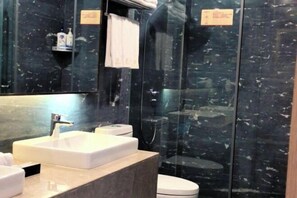 Un baño moderno con lavamanos blanco, un espejo, inodoro y ducha con mampara de vidrio.