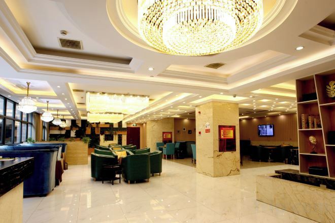 A hotel lobby with a reception desk, seating area, and a chandelier.
