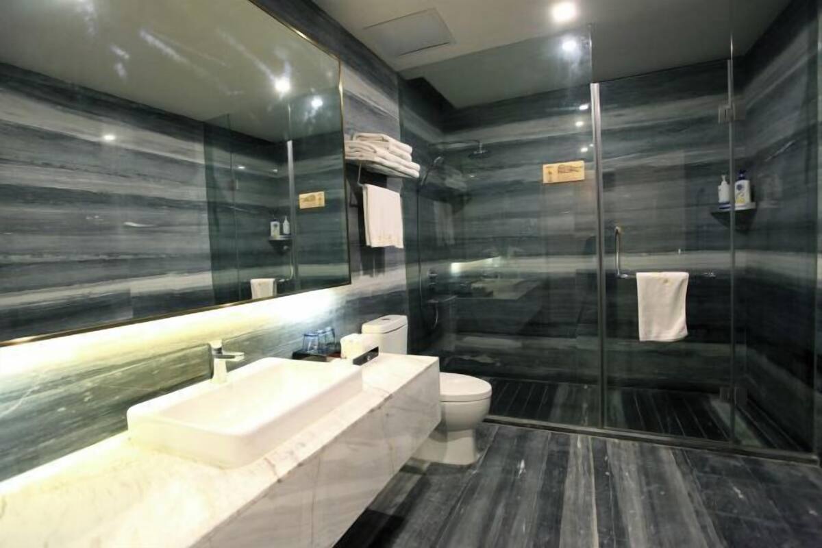 A modern bathroom with a glass-enclosed shower, a white sink, and a marble backsplash.