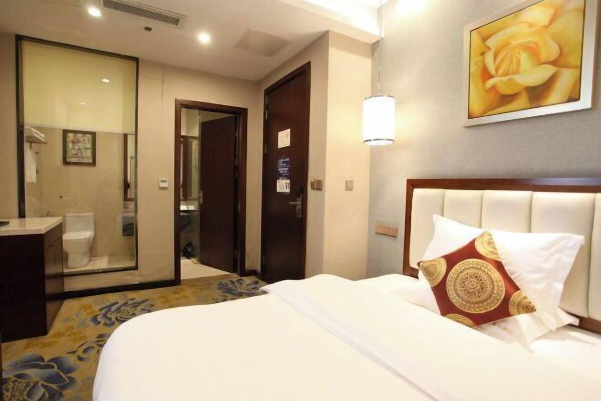 A hotel room with a bed, a bathroom, and a door leading to another room.
