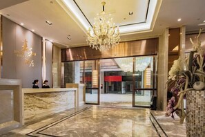 Zona de recepción de hotel con suelo de mármol, candelabro y mostrador.