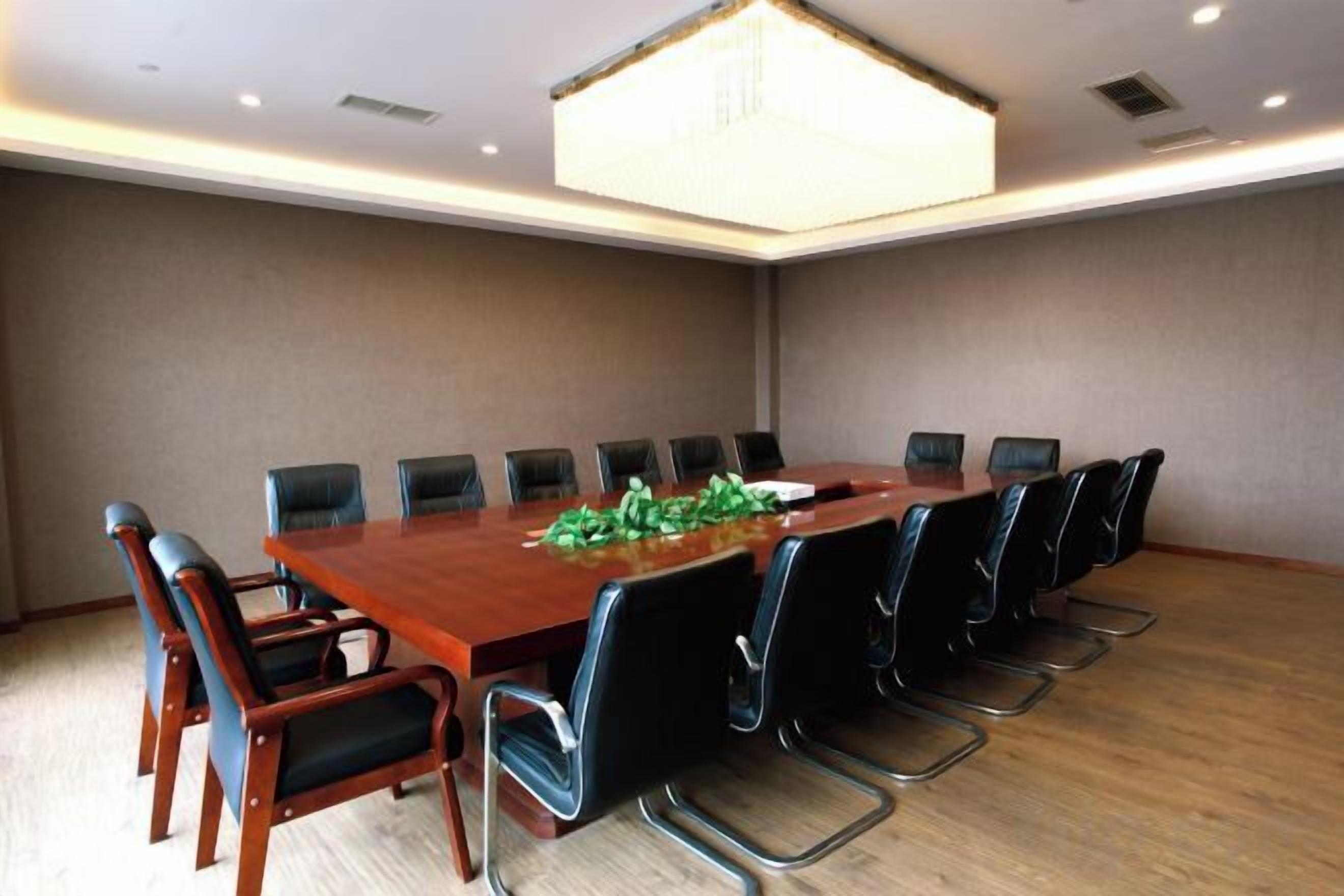 A conference room with a long table, black chairs, and a chandelier.