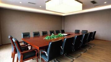 A conference room with a long table, black chairs, and a chandelier.