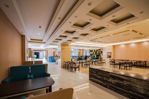A hotel lobby with a marble reception desk, seating areas, and a modern ceiling design. - Jiahe Hotel (Qionglai)