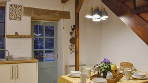 Una cucina con un tavolo imbandito per la colazione, una sveglia appesa al muro e un soffitto in legno rustico.