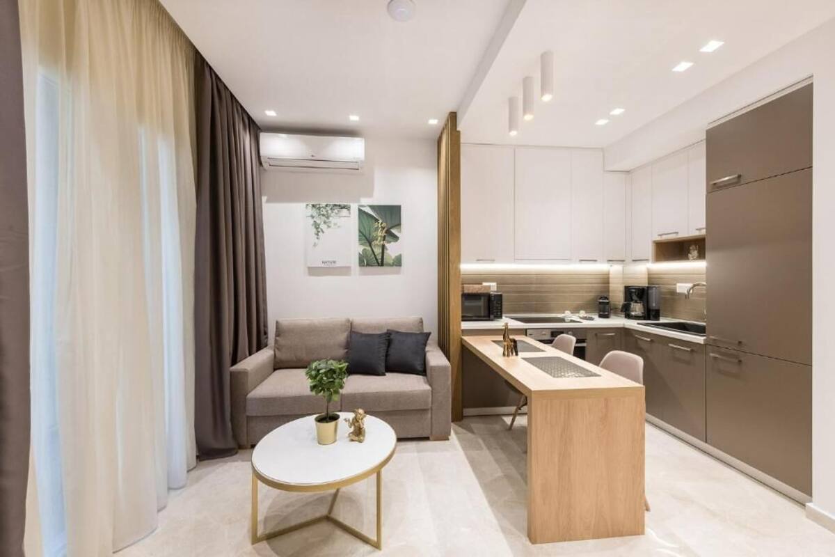 A modern apartment with a kitchenette, a sofa, a coffee table, and a dining area.