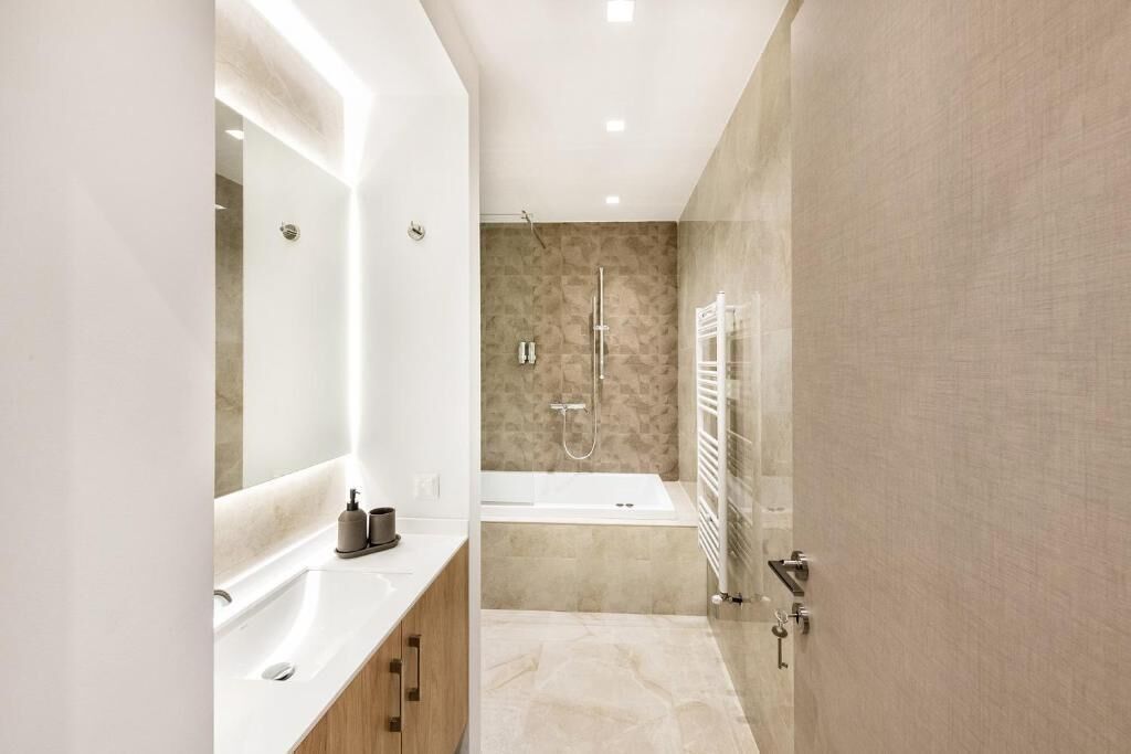 Un baño moderno con un espejo grande, una bañera y una zona de ducha.