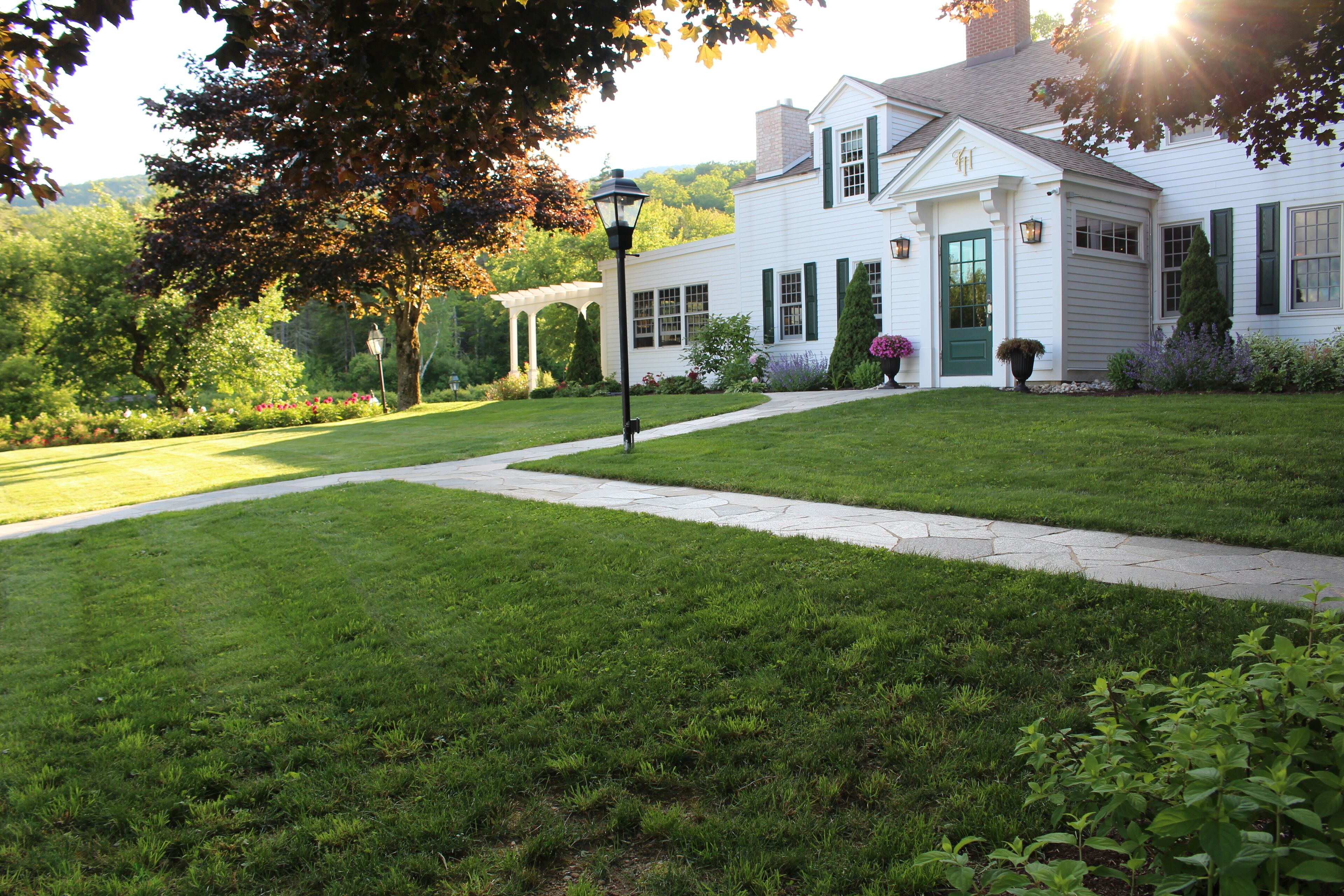 A white house with a green door and a well-maintained lawn.