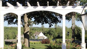 Una pérgola blanca con un camino de piedra que lleva a una casa.