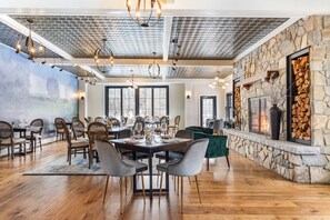 A spacious dining area with a high ceiling, stone walls, and a fireplace. - The Hermitage Inn Vermont (West Dover)