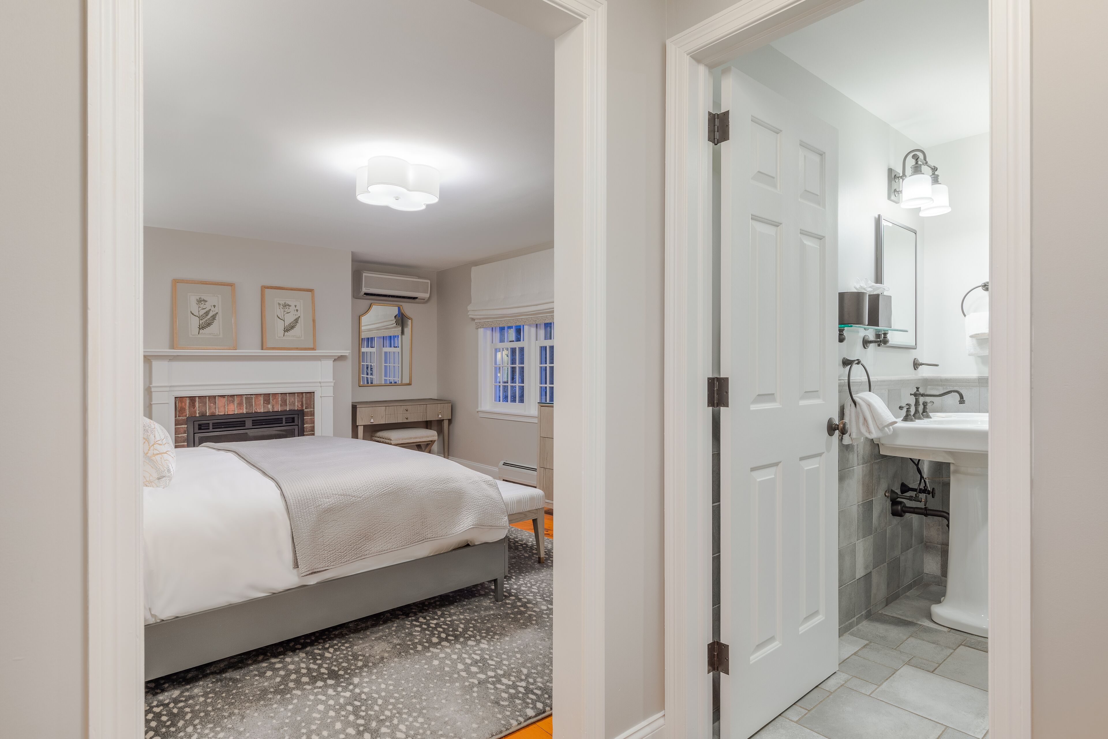 A bedroom with a bed, a bedside table, a mirror, and a window.