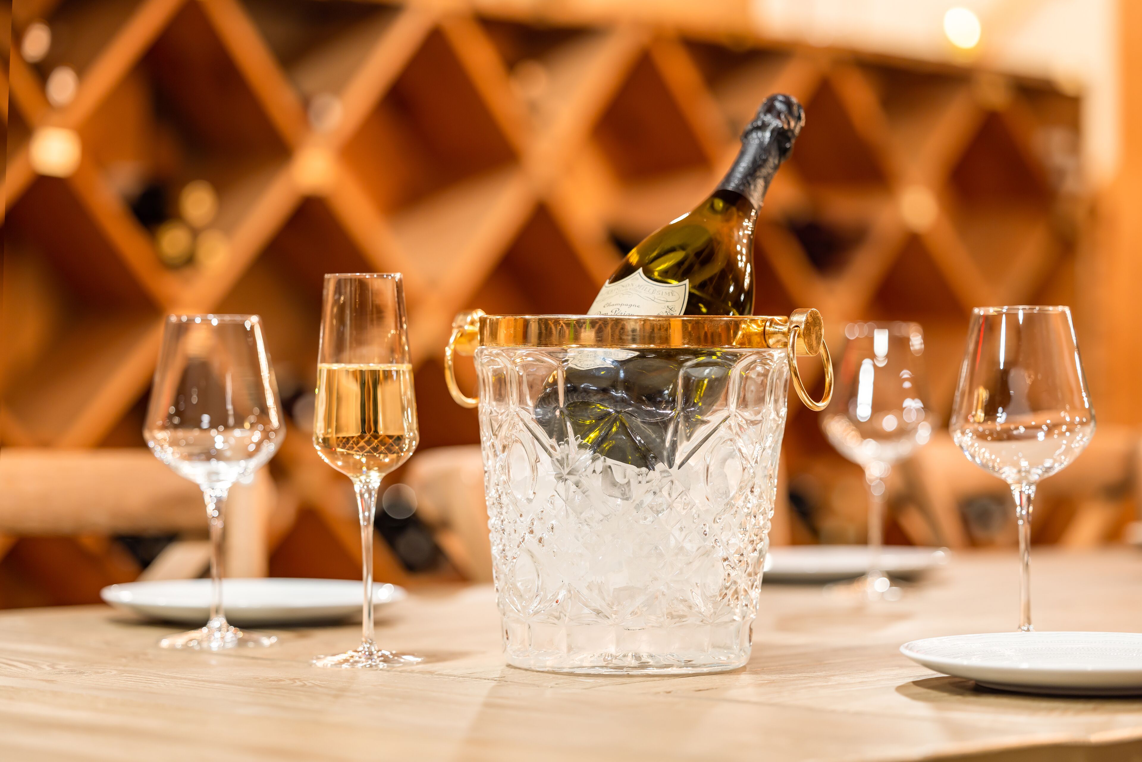 A table with a glass container filled with ice and a bottle of champagne being poured into it.