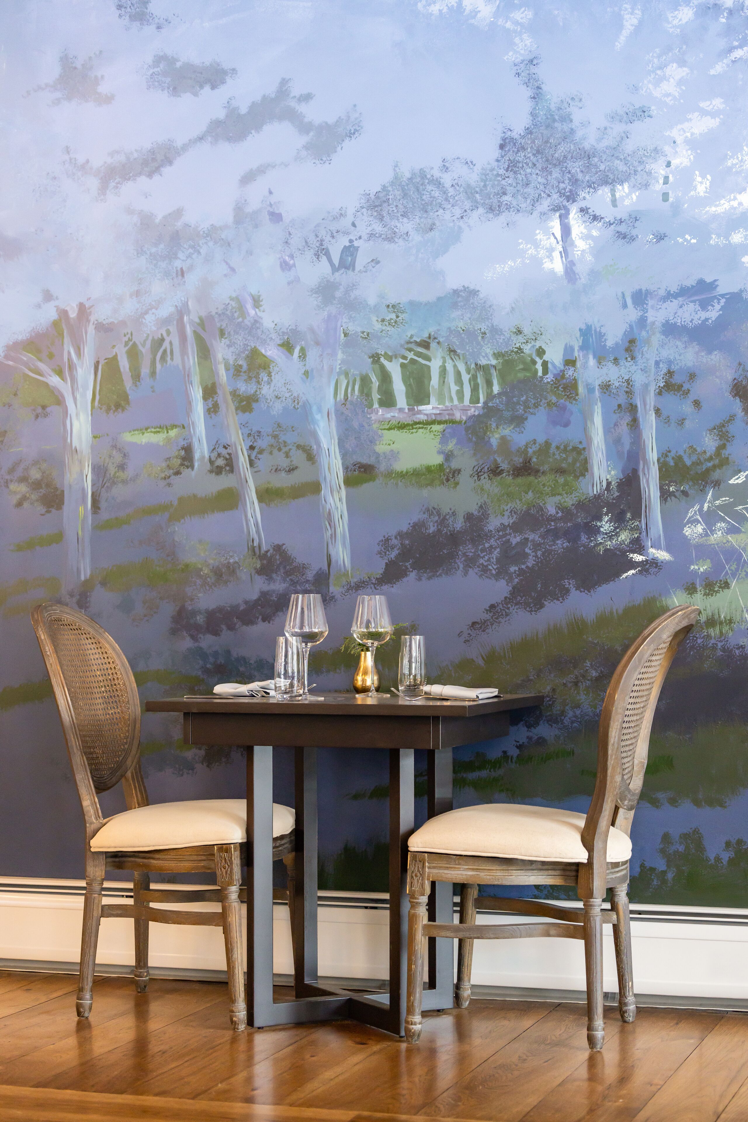Una mesa de comedor con dos sillas y un cuadro de una cascada en la pared de fondo.