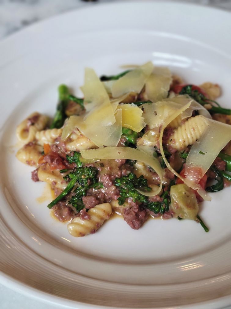 A plate of pasta with greens and cheese.