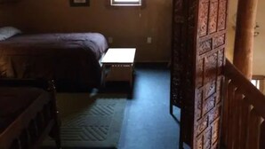 Un dormitorio con cama, una mesita, alfombra y un armario de madera.