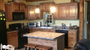 Una cocina rústica con armarios de madera, una isla con encimera de granito y un comedor con mesa y sillas.
