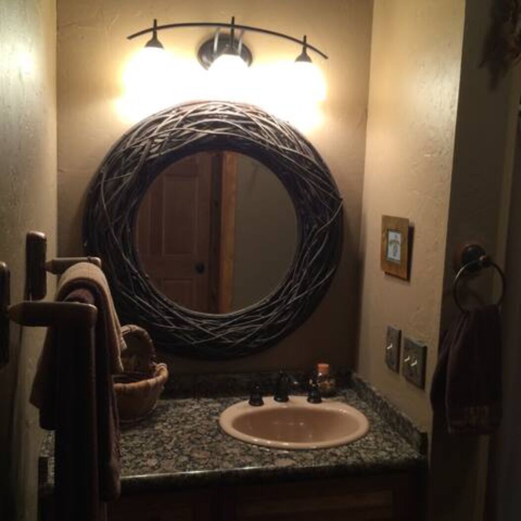 Une salle de bain avec un miroir rond, un lavabo et un porte-serviettes.