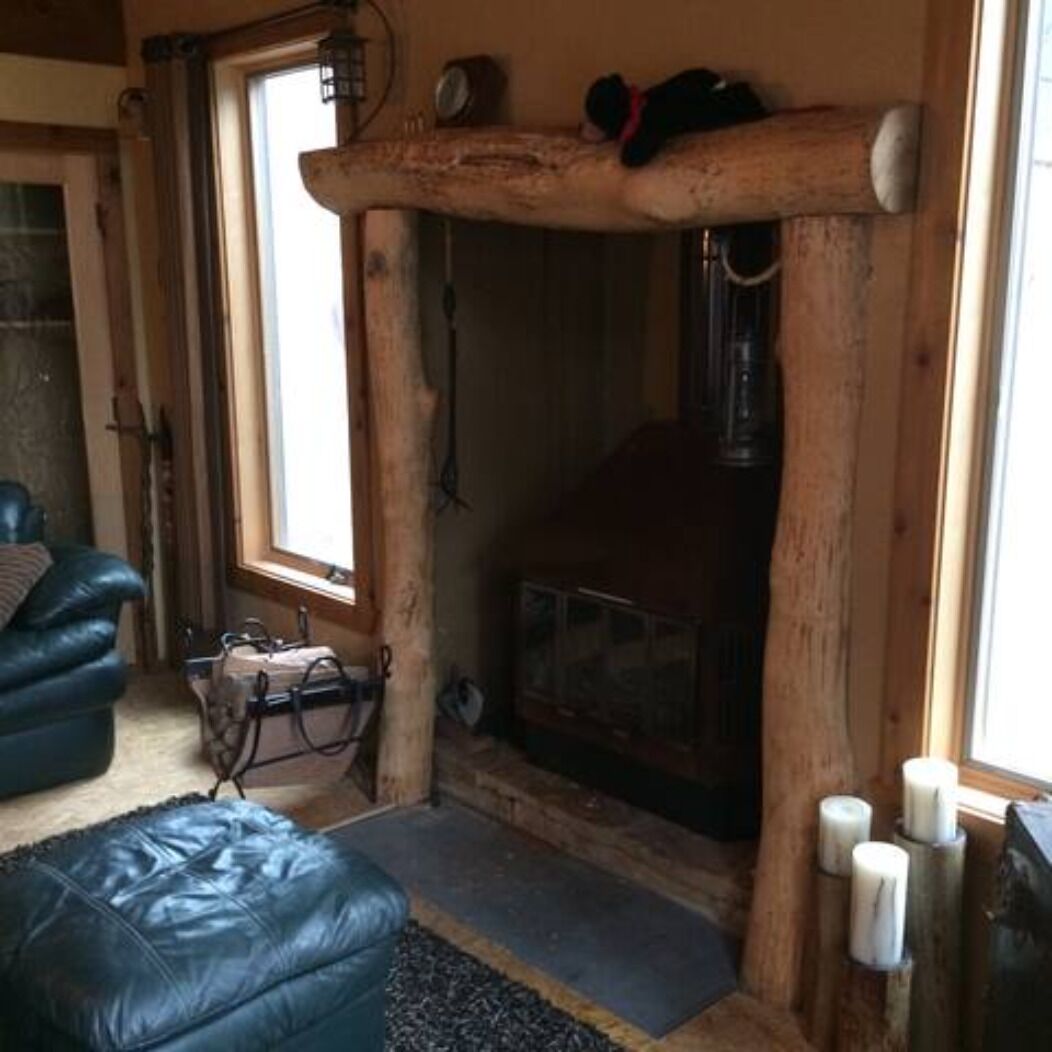 Une pièce chaleureuse avec une cheminée, un canapé en cuir et une structure en bois.